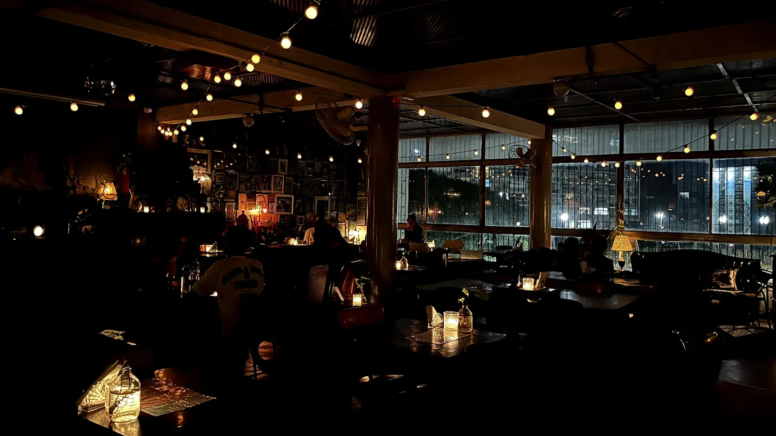 Ambiente interno do bar A Balsa, com iluminação intimista e mesas diversas